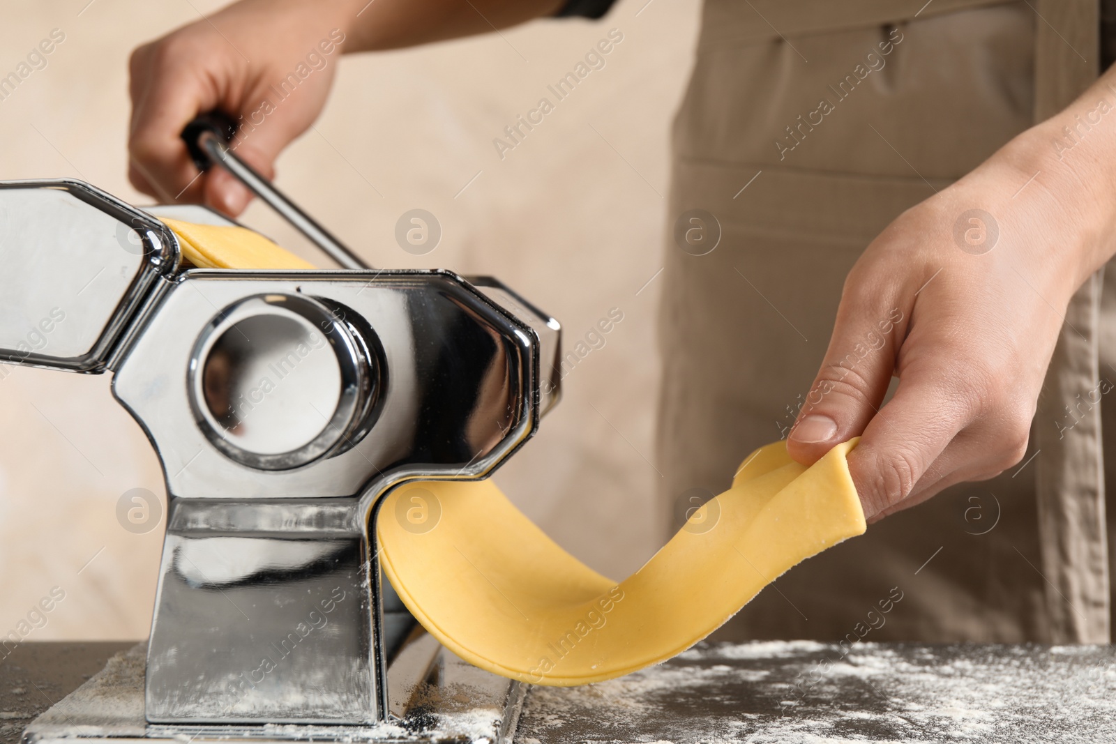 Photo of Woman preparing dough with pasta maker machine at table, closeup