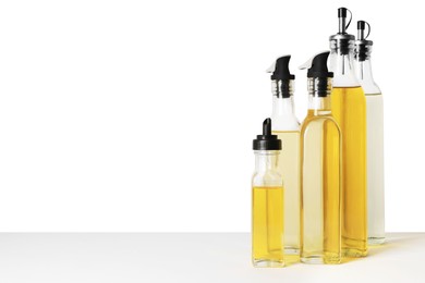 Bottles of different cooking oils on white background, space for text