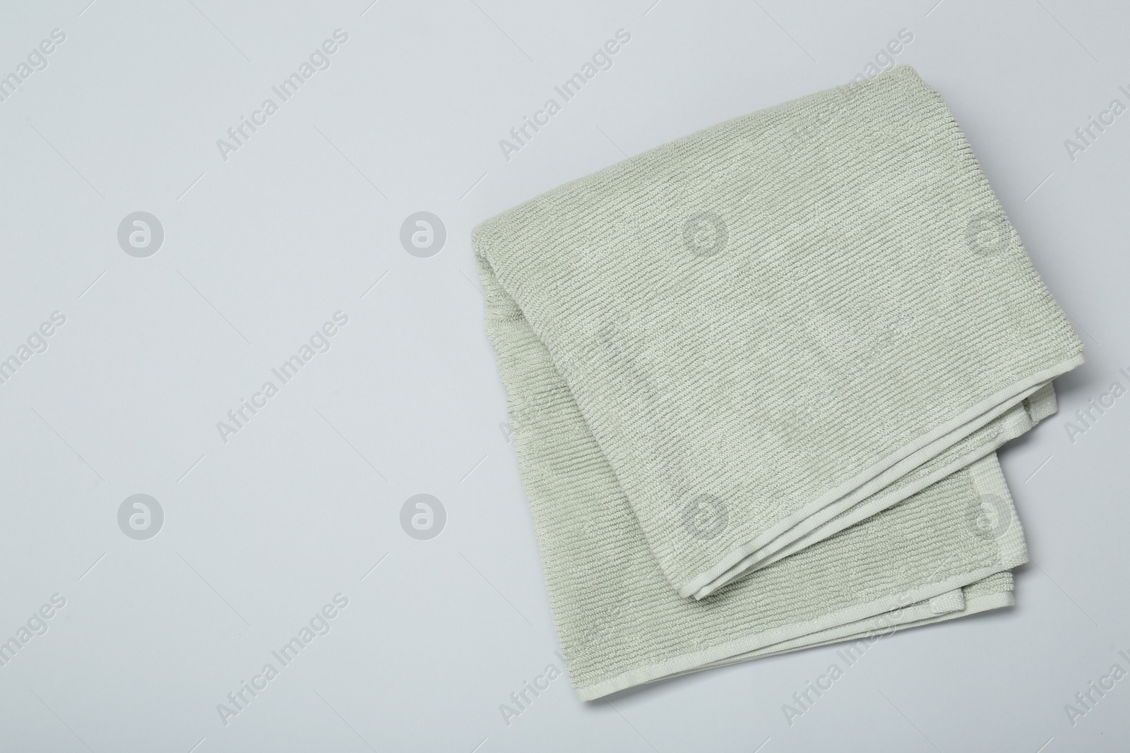 Photo of Soft green towel on light grey background, top view. Space for text