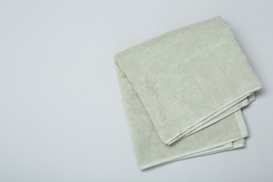 Photo of Soft green towel on light grey background, top view. Space for text