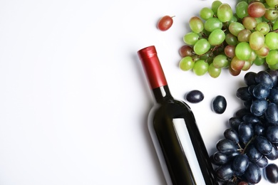 Photo of Fresh ripe juicy grapes, bottle of red wine and space for text on white background, top view