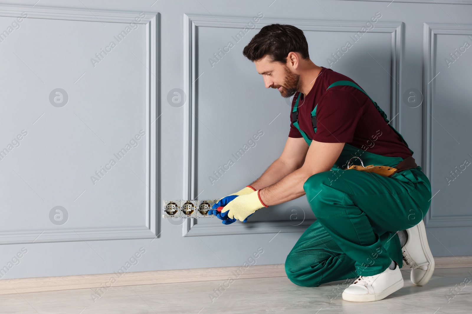 Photo of Electrician with screwdriver repairing power sockets indoors