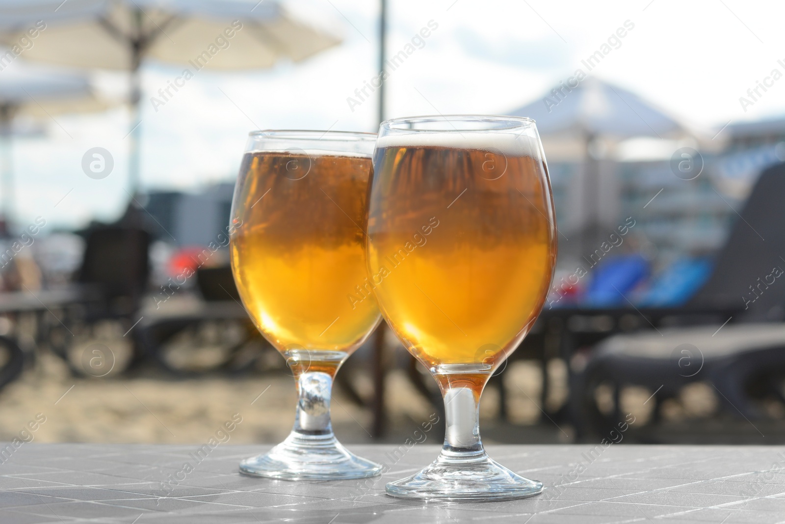 Photo of Cold beer in glass on beach, closeup