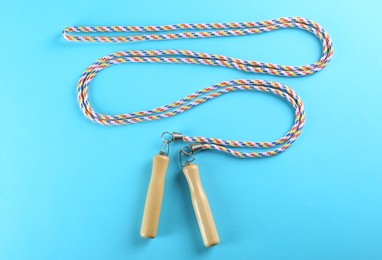 Photo of Skipping rope on light blue background, top view. Sports equipment