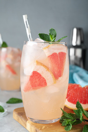 Photo of Glass of fresh cocktail with grapefruit on table, closeup