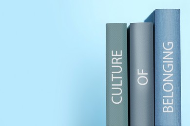 Image of Books with phrase Culture of Belonging on light blue background, space for text