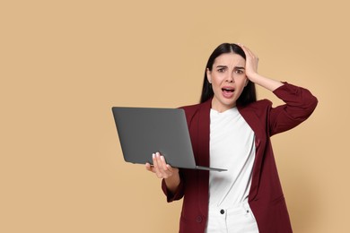 Photo of Shocked woman with laptop on beige background