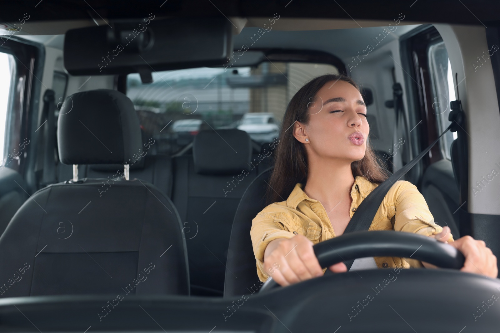 Photo of Listening to radio. Beautiful woman enjoying music in car, view through windshield