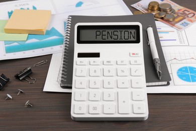 Photo of Calculator, notebook, papers, notes, pen and money on wooden table. Pension planning
