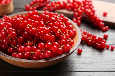 Photo of Delicious red currants in bowl on dark wooden table, closeup