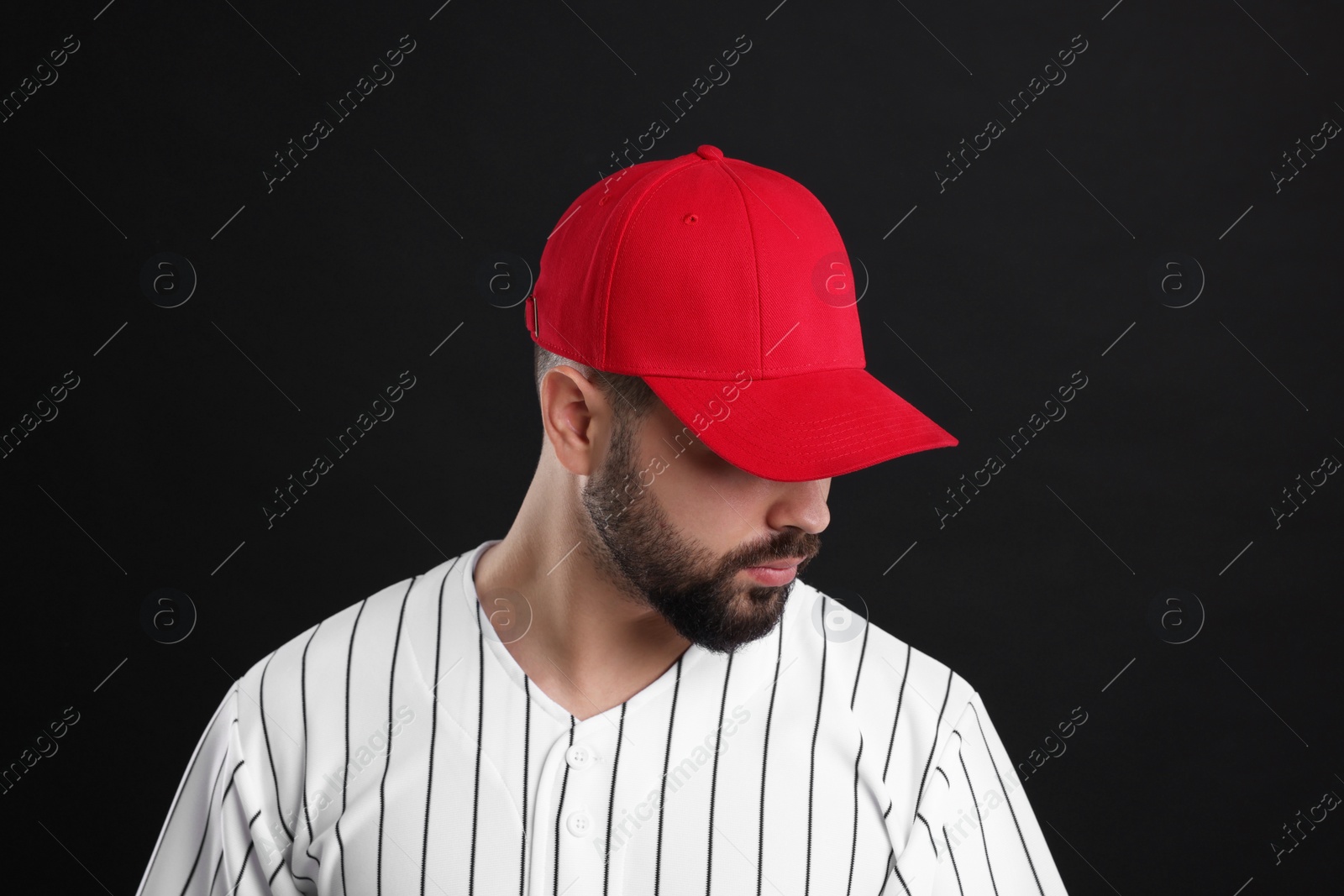 Photo of Man in stylish red baseball cap on black background