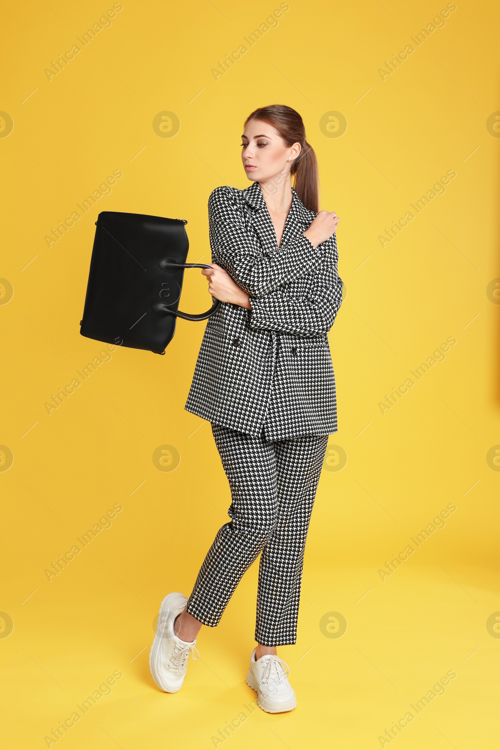 Photo of Beautiful young woman with stylish bag on yellow background