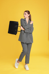 Photo of Beautiful young woman with stylish bag on yellow background