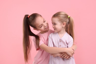 Portrait of cute little sisters on pink background