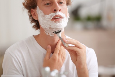 Young handsome man shaving in bathroom