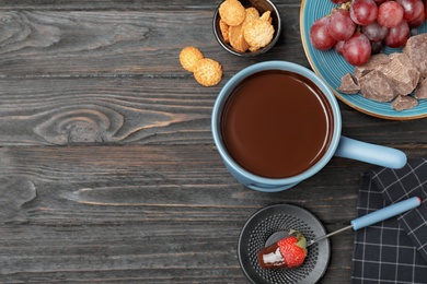 Photo of Flat lay composition with chocolate fondue and space for text on dark wooden background