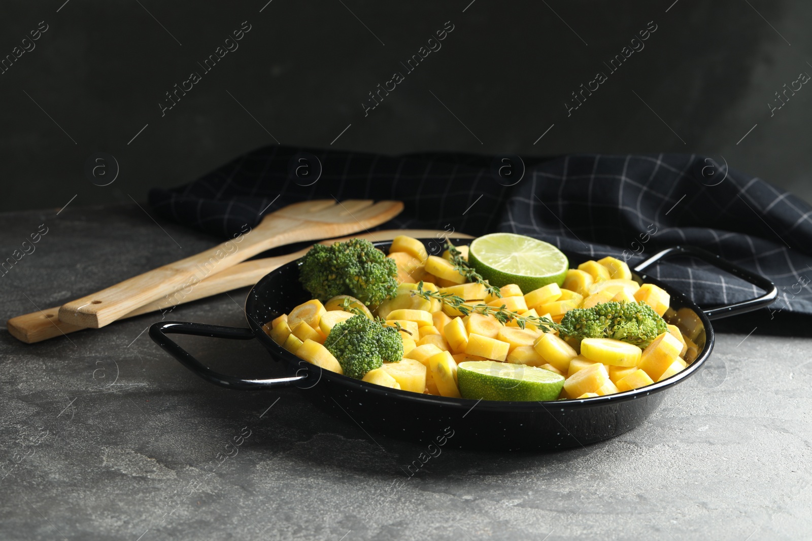 Photo of Raw yellow carrot with limes and broccoli on grey table