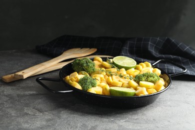 Photo of Raw yellow carrot with limes and broccoli on grey table