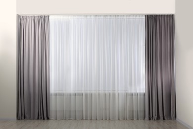 Photo of Light grey window curtains and white tulle indoors