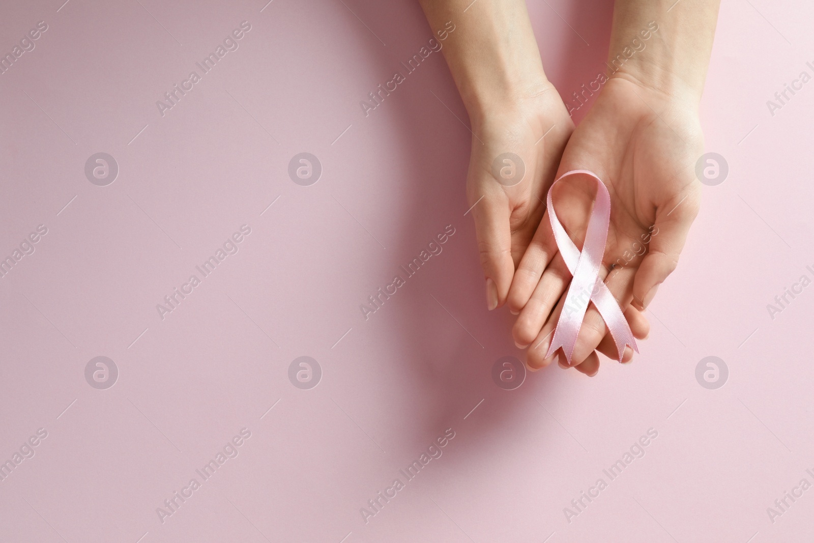 Photo of Woman holding pink ribbon on color background, top view with space for text. Breast cancer awareness