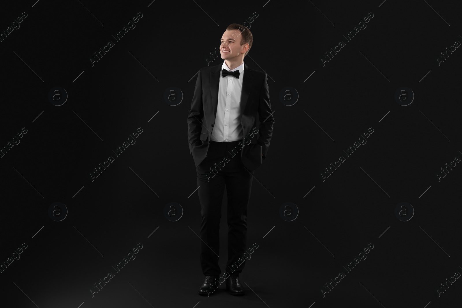 Photo of Handsome young man in stylish suit on black background