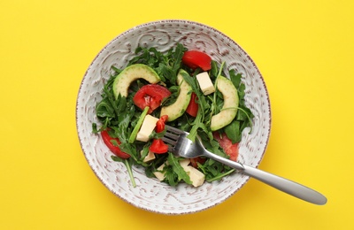 Photo of Bowl with fresh vegetable salad on color background, top view. Healthy diet