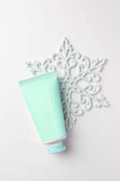 Winter skin care. Hand cream and decorative snowflake on white background, top view