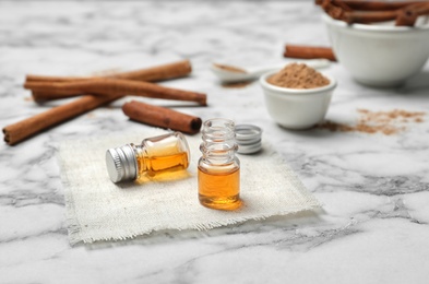 Photo of Bottles with cinnamon oil and sticks on light background