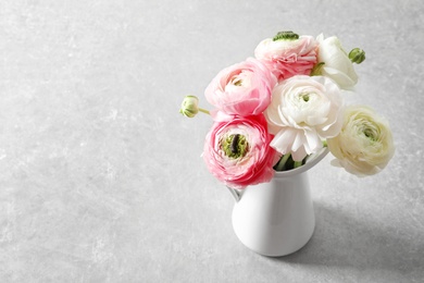 Photo of Vase with beautiful ranunculus flowers on light background