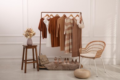 Photo of Rack with stylish clothes and shoes in dressing room. Interior design