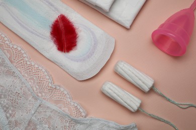 Photo of Woman's panties, menstrual pad, cup and tampons on peach background, flat lay