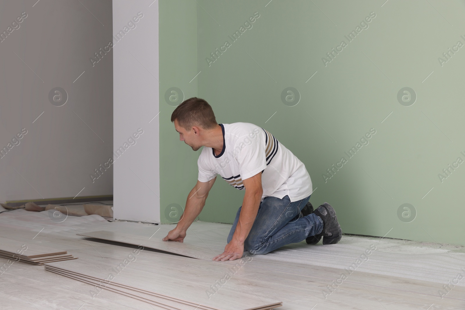 Photo of Man installing new laminate flooring in room