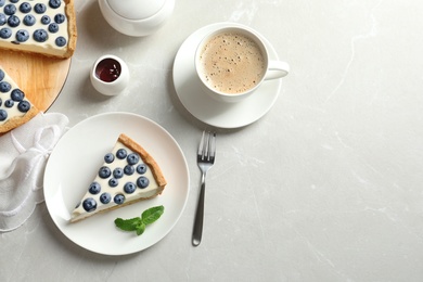 Photo of Flat lay composition with piece of tasty blueberry cake and space for text on gray table