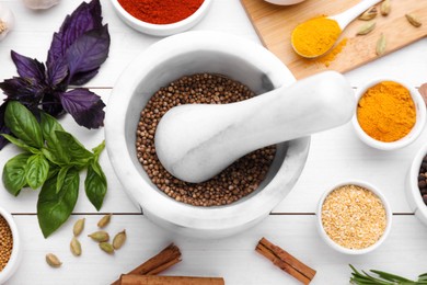 Photo of Mortar with pestle and different spices on white wooden table, flat lay
