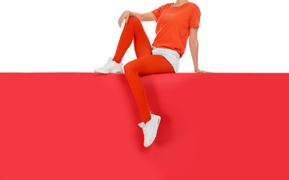 Photo of Woman wearing red tights and stylish shoes sitting on color background, closeup