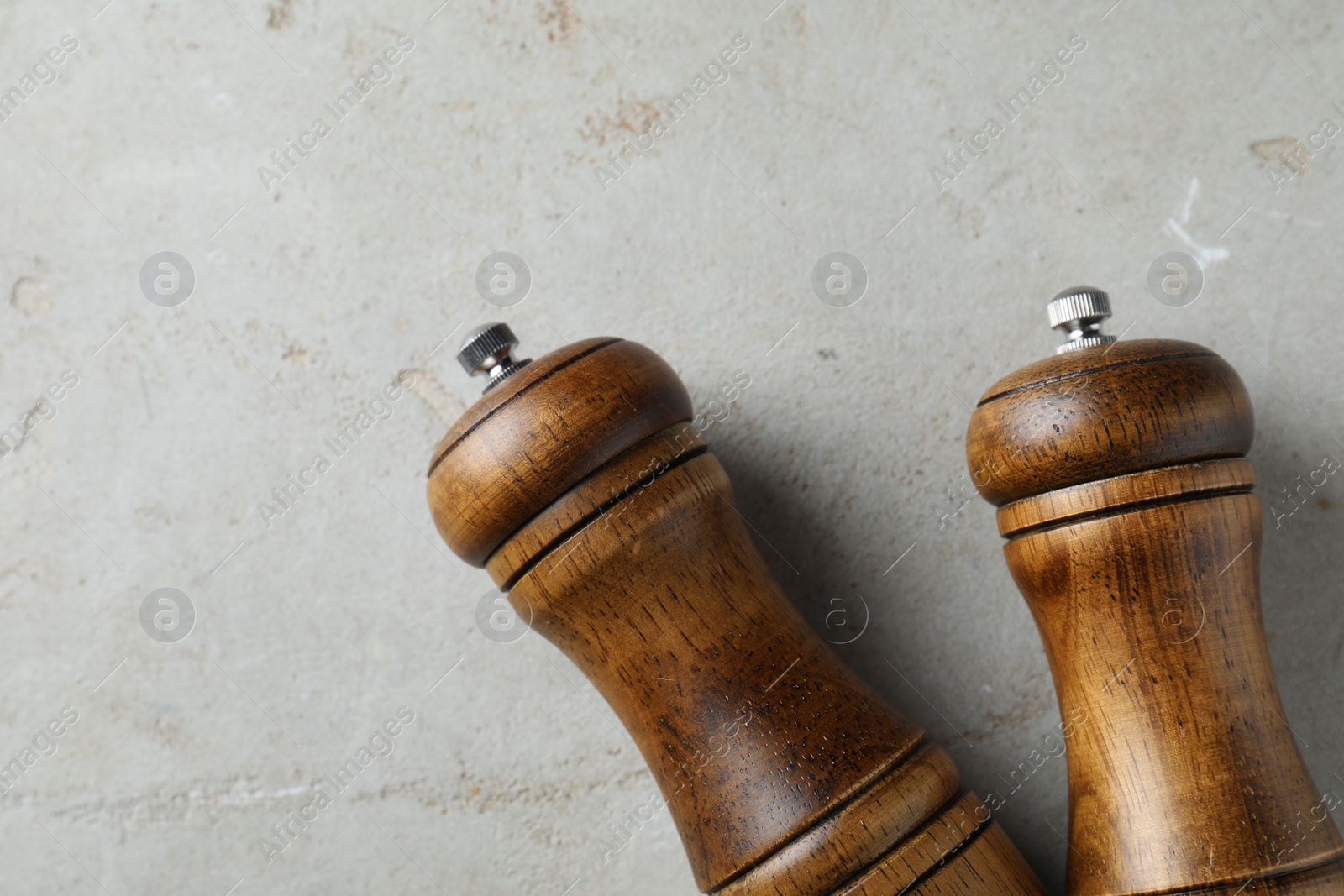 Photo of Wooden salt and pepper shakers on light textured table, top view. Space for text