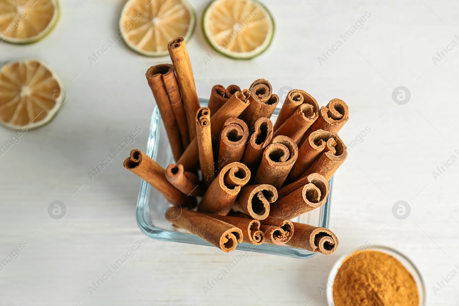 Photo of Bowl with aromatic cinnamon sticks on light background, closeup