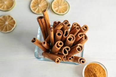 Bowl with aromatic cinnamon sticks on light background, closeup