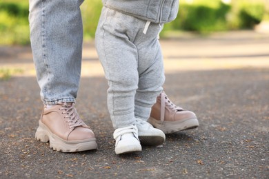 Mother teaching her baby how to walk outdoors, closeup
