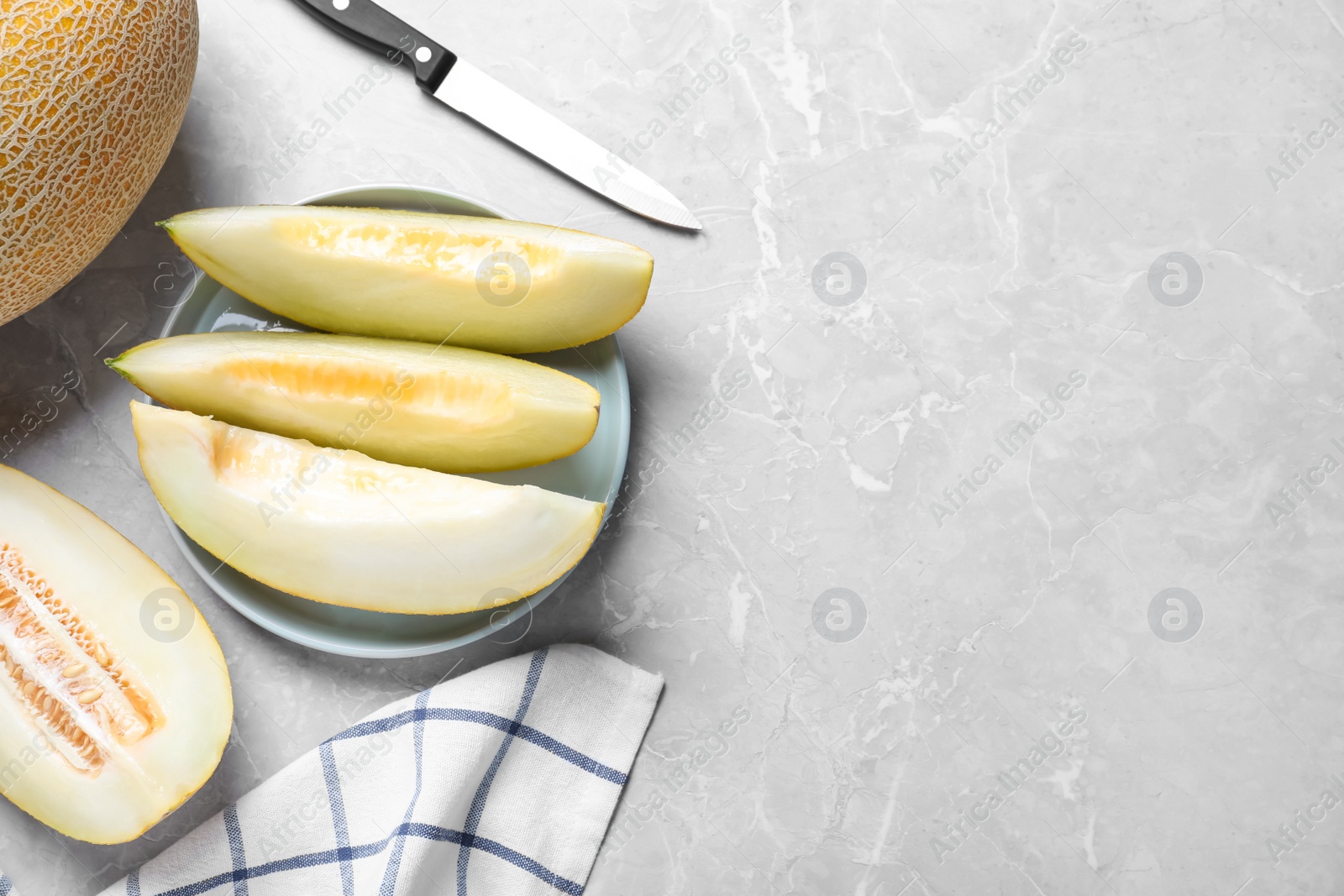 Photo of Pieces of delicious honeydew melon on light grey marble table, flat lay. Space for text