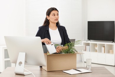 Unemployment problem. Woman with box of personal belongings at table in office