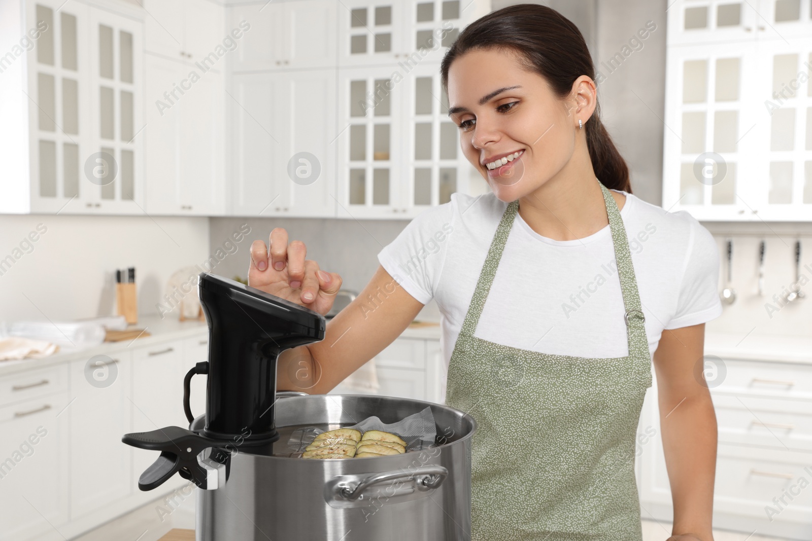 Photo of Woman using thermal immersion circulator in kitchen. Sous vide cooking