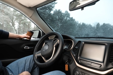 Photo of Young man with coffee inside car, closeup