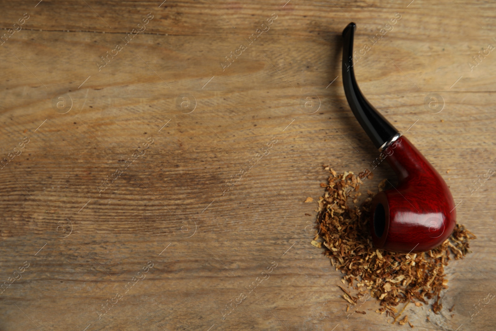 Photo of Classic smoking pipe with tobacco on wooden table, flat lay. Space for text