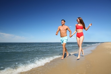 Photo of Woman in bikini and her boyfriend on beach, space for text. Happy couple