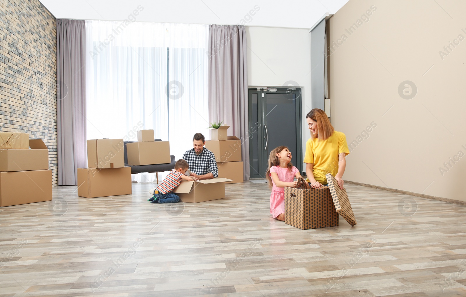 Photo of Family unpacking cardboard boxes in their new house. Moving day