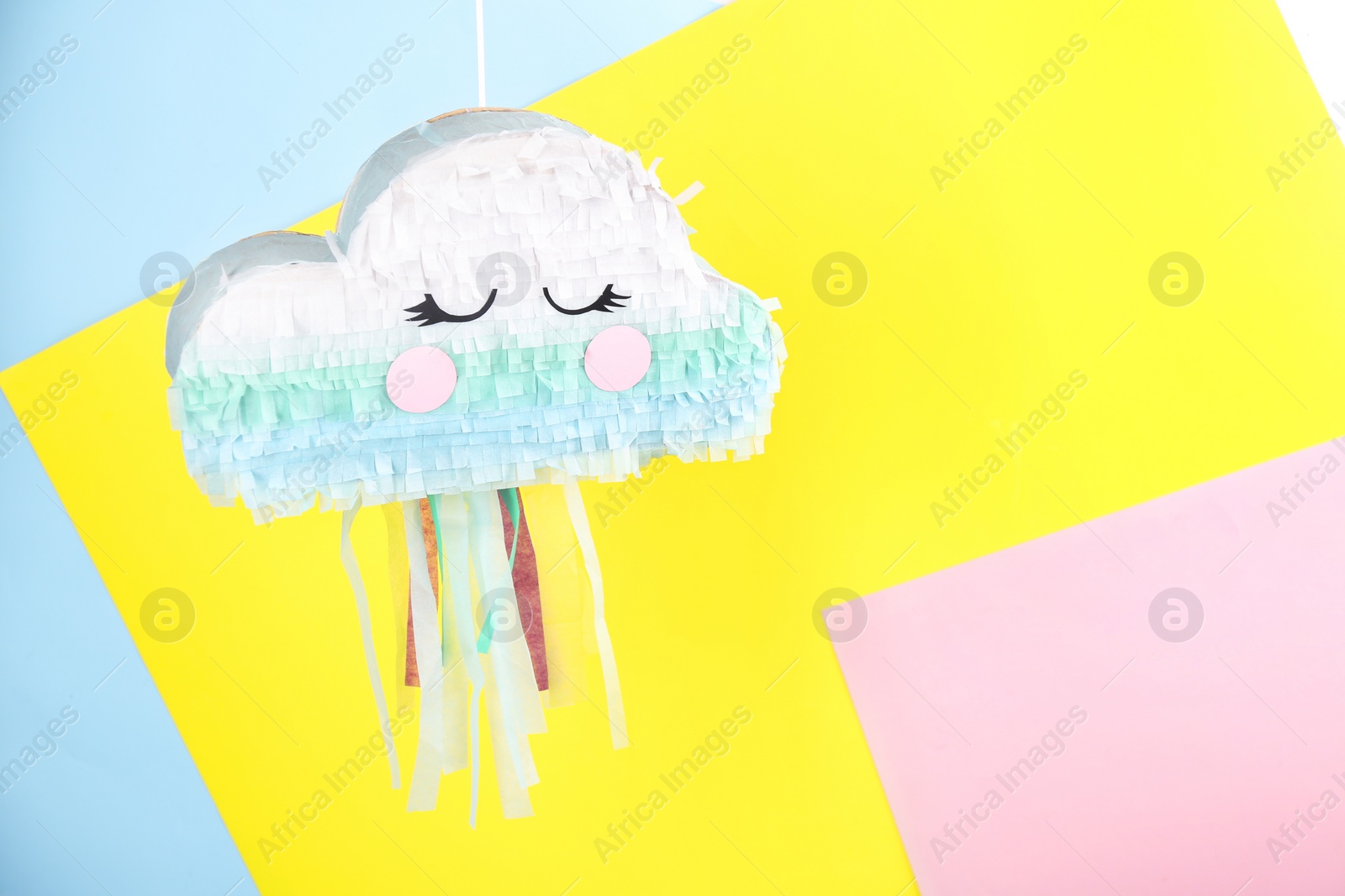 Photo of Cloud shaped pinata hanging on color background. Space for text