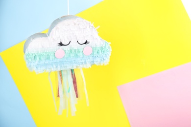 Photo of Cloud shaped pinata hanging on color background. Space for text