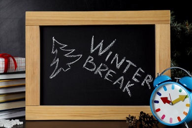 Photo of Blackboard with text Winter Break and Christmas decor on table. School holidays