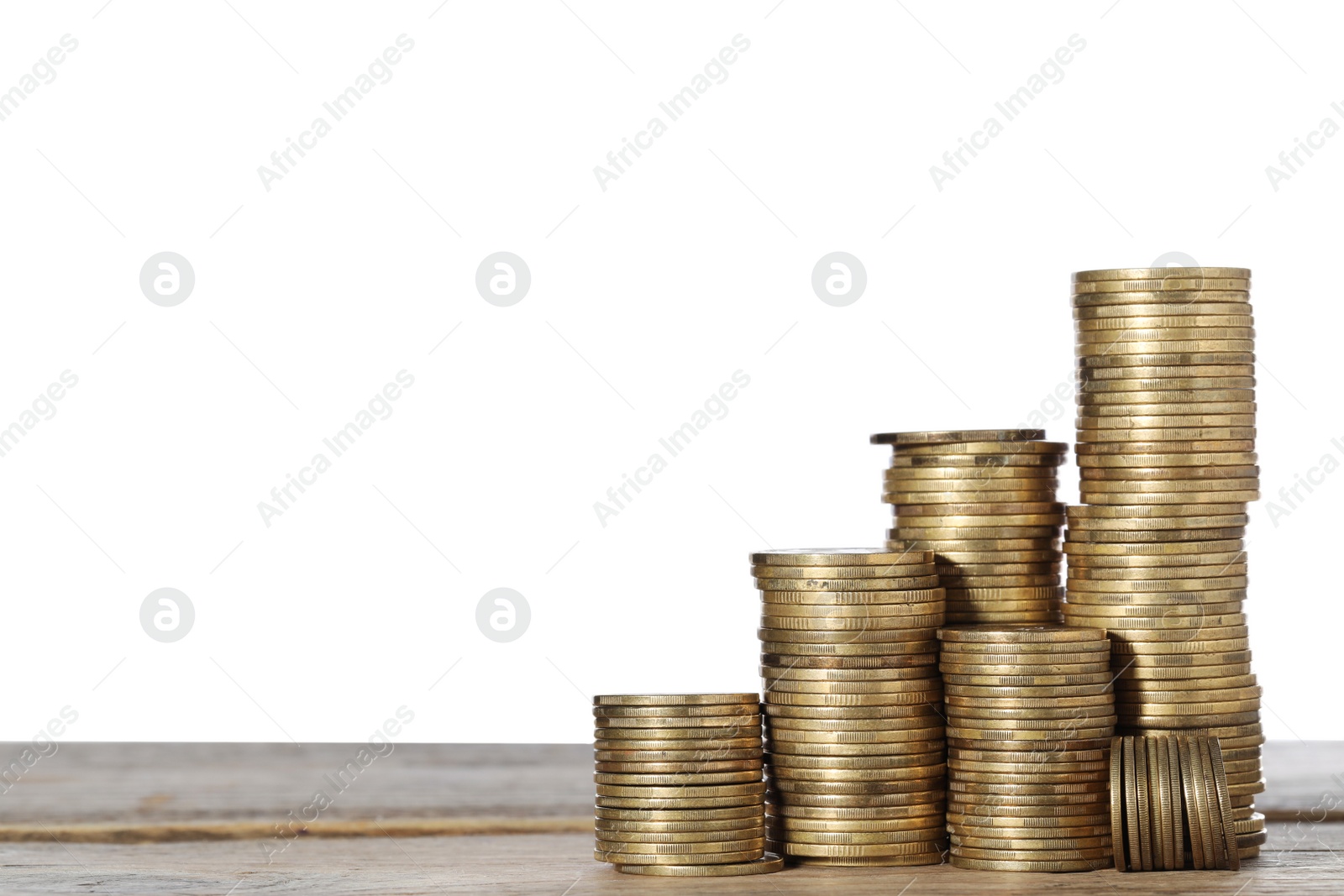 Photo of Many golden coins stacked on wooden table against white background